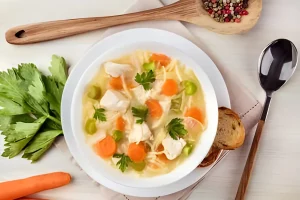 Person serving Chicken Noodle Soup into bowls