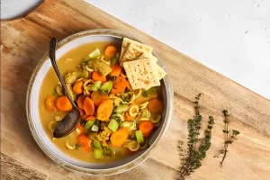 Gluten-free chicken noodle soup in a white bowl with parsley garnish.