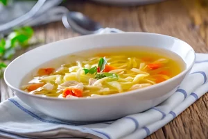 A close-up of simmering Chicken Noodle Soup