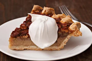 Homemade pecan pie with a flaky crust, served with vanilla ice cream