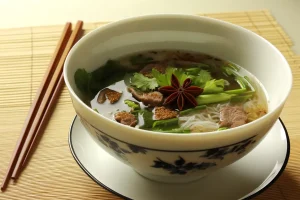 Asian-influenced Saturday Soup in a porcelain bowl, featuring spices and herbs.